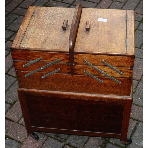 1108 - An oak work box with double hinged expanding top over 2 panel doors, on castors, 51cm wide closed, 3... 