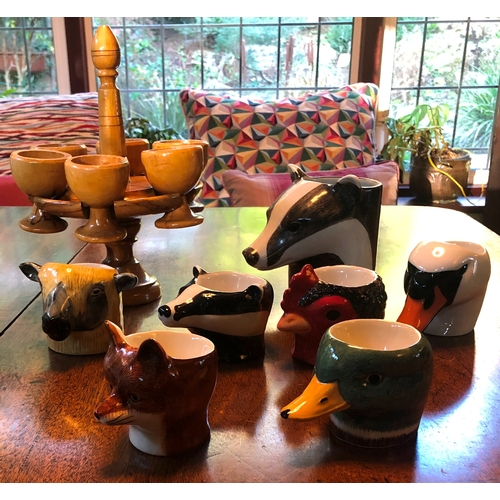 1189 - 6 novelty egg cups and 1 mug in the shape of animal heads and a wooden stand with 6 wooden egg cups.