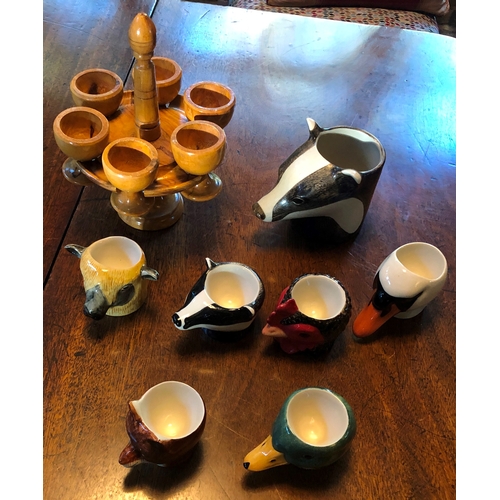 1189 - 6 novelty egg cups and 1 mug in the shape of animal heads and a wooden stand with 6 wooden egg cups.