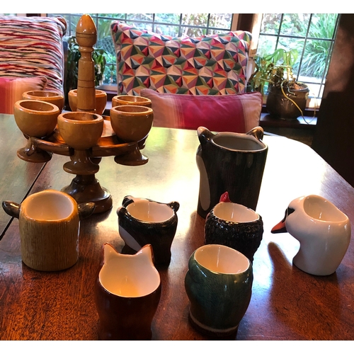 1189 - 6 novelty egg cups and 1 mug in the shape of animal heads and a wooden stand with 6 wooden egg cups.