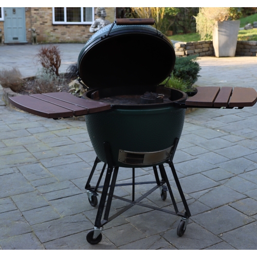 1287 - A Big Green Egg barbeque on wheels, 137cm high overall, 2 drop-down side shelves,  griddle pan and g... 