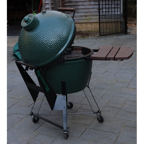 1287 - A Big Green Egg barbeque on wheels, 137cm high overall, 2 drop-down side shelves,  griddle pan and g... 