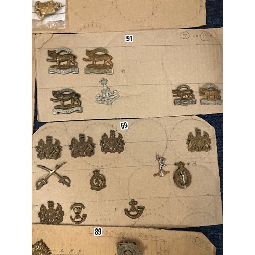 846 - A quantity of various military and other cap badges etc mounted on 26 cut down boards