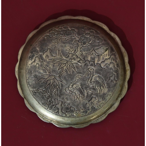 566 - An Oriental silver coloured metal round scallop shaped compact with raised dragon decoration, hinged... 