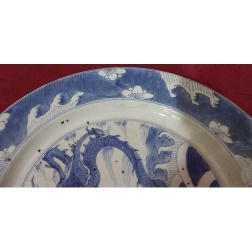 106 - An 18th Century blue and white plate with dragon, fish and wave decoration, 26.7cm diameter (restore... 