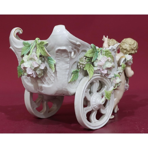 185 - A 19th Century Continental china comport in the form of 2 cupids pulling a chariot with encrusted fl... 