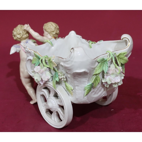 185 - A 19th Century Continental china comport in the form of 2 cupids pulling a chariot with encrusted fl... 