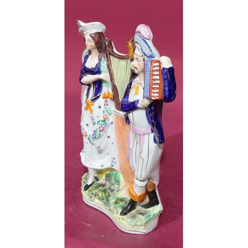 216 - A 19th Century Staffordshire group of gentleman and lady holding a harp and accordion, 39cm high