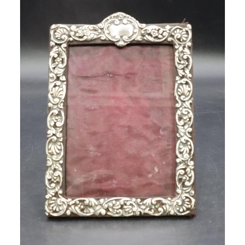 324 - A Birmingham silver mounted freestanding photograph frame with embossed floral, leaf and scroll deco... 