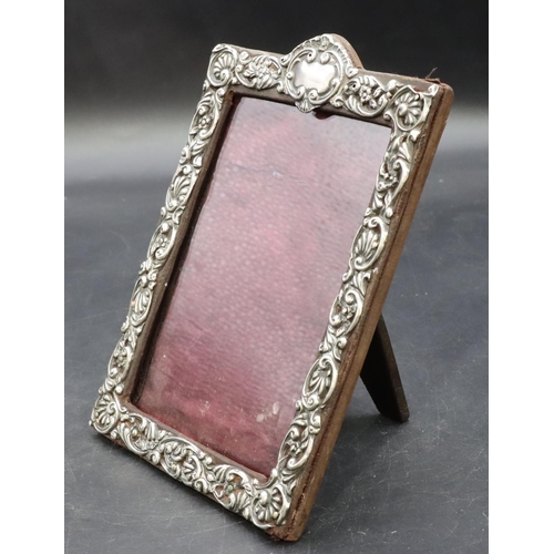 324 - A Birmingham silver mounted freestanding photograph frame with embossed floral, leaf and scroll deco... 