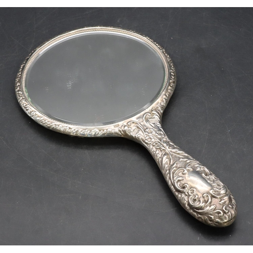 327 - A Birmingham silver hand mirror with embossed cupid, floral and scroll decoration