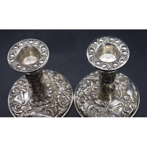 329 - A pair of Birmingham silver dwarf candlesticks with embossed leaf and scroll decoration on round bas... 