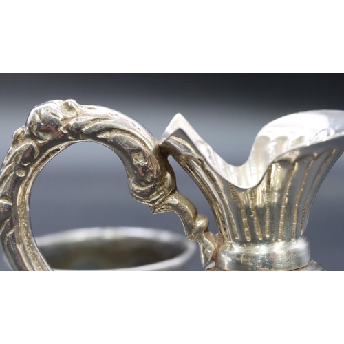 341 - A silver coloured metal small round bulbous shaped ewer with embossed floral and scroll decoration, ... 