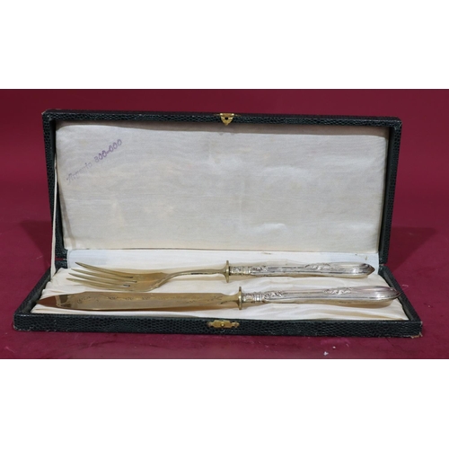 377 - A pair of 800 silver coloured metal handled fish servers with engraved scroll decoration in fitted g... 