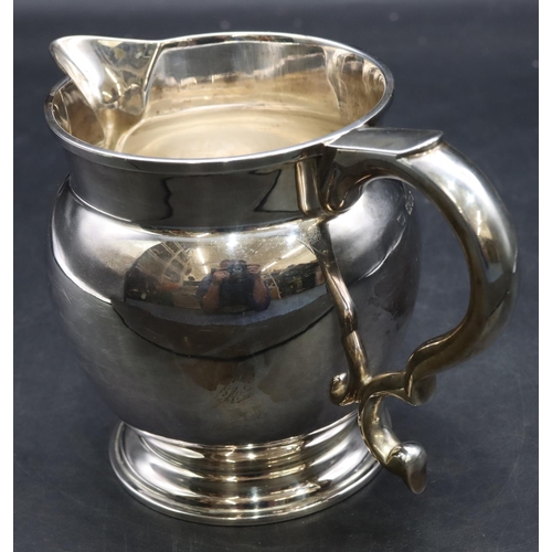 414 - A George V silver round bulbous shaped jug with scroll handle on sweeping foot, London 1931, stamped... 