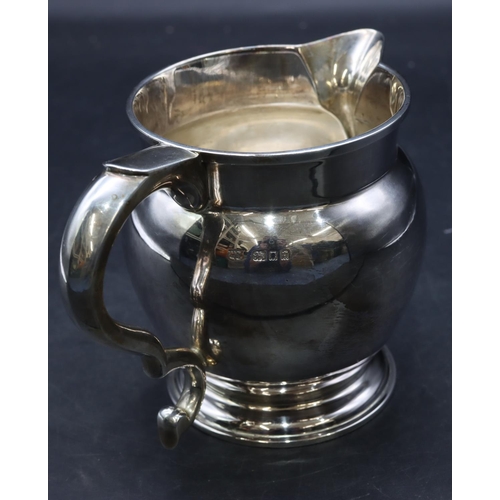 414 - A George V silver round bulbous shaped jug with scroll handle on sweeping foot, London 1931, stamped... 