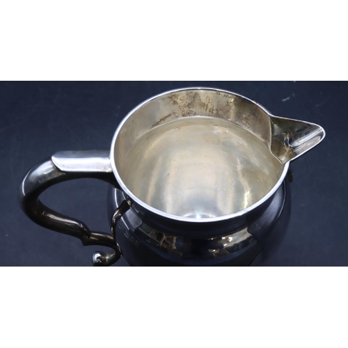 414 - A George V silver round bulbous shaped jug with scroll handle on sweeping foot, London 1931, stamped... 