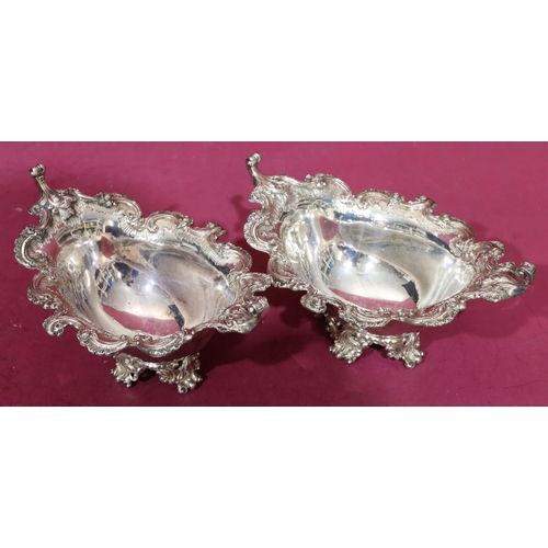 416 - A pair of Victorian oval scallop shaped bonbon dishes with raised floral, leaf and scroll rims on sp... 