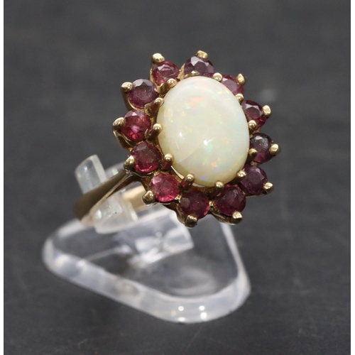 529 - A 9ct gold ladies' oval cluster ring set with centre opal surround by red stones, Size M, 3.5 grams