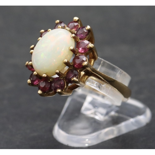 529 - A 9ct gold ladies' oval cluster ring set with centre opal surround by red stones, Size M, 3.5 grams