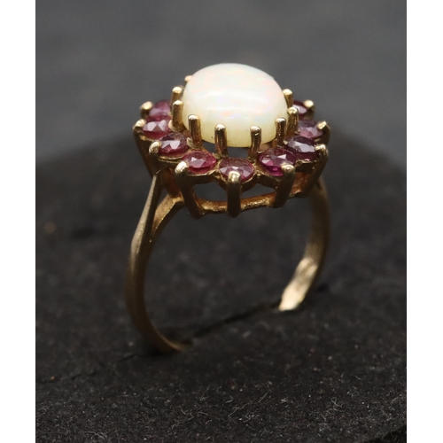 529 - A 9ct gold ladies' oval cluster ring set with centre opal surround by red stones, Size M, 3.5 grams