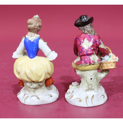 54 - A pair of Sitzendorf porcelain figures of a seated gentleman and lady with allover encrusted floral ... 