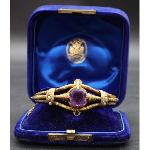 550 - A 19th Century Russian high carat gold hinged bangle set with centre amethyst flanked by half pearls... 