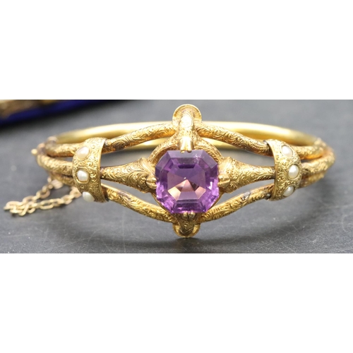 550 - A 19th Century Russian high carat gold hinged bangle set with centre amethyst flanked by half pearls... 