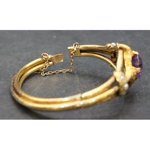 550 - A 19th Century Russian high carat gold hinged bangle set with centre amethyst flanked by half pearls... 