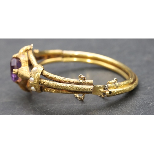 550 - A 19th Century Russian high carat gold hinged bangle set with centre amethyst flanked by half pearls... 