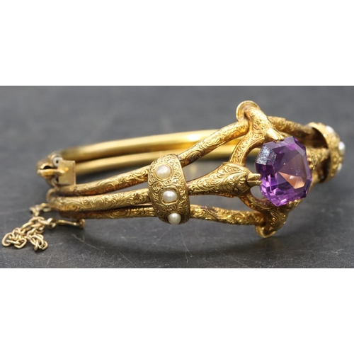 550 - A 19th Century Russian high carat gold hinged bangle set with centre amethyst flanked by half pearls... 