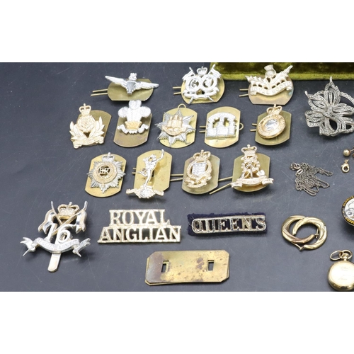 555 - A circular locket, a small quantity of various jewellery and a small quantity of various cap badges