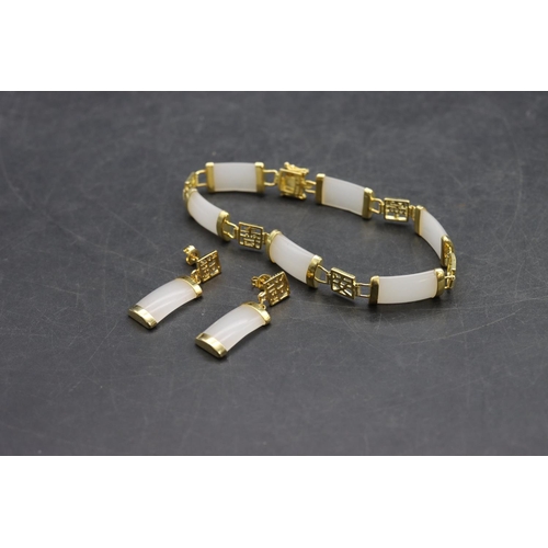 571 - A gilt metal and white hardstone panelled bracelet with a pair of matching earrings (3)