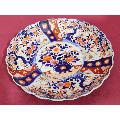 73 - An Imari round scallop shaped plate on white, blue and red ground with vase, floral, leaf and scroll... 