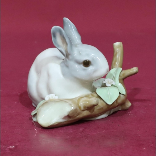 75 - A Lladro figure of a rabbit resting next to a log (encrusted flowers slight chips), 12cm wide