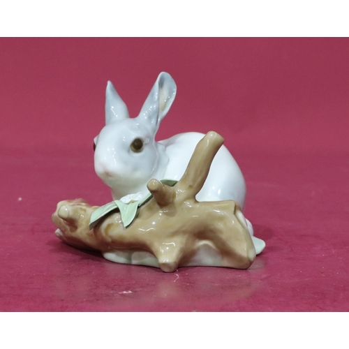 75 - A Lladro figure of a rabbit resting next to a log (encrusted flowers slight chips), 12cm wide