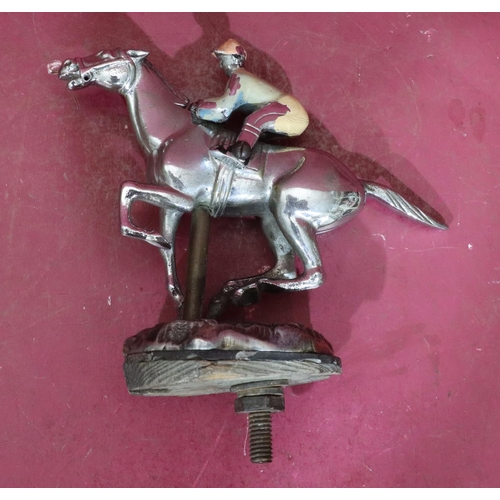 811 - A car mascot in the form of a jockey on horseback, 13.5cm wide, 14.5cm high including screw