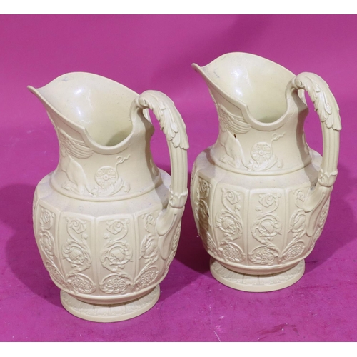 82 - A pair of Buff Canova round bulbous shaped jugs with raised mythical winged beasts, scroll and flora... 