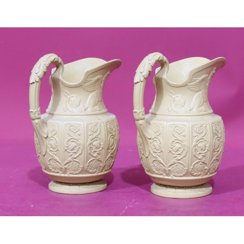 82 - A pair of Buff Canova round bulbous shaped jugs with raised mythical winged beasts, scroll and flora... 