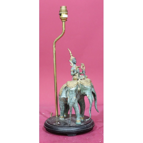 824 - An Eastern bronze and gilt metal table lamp in the form of a figure riding 3-headed elephant, mounte... 