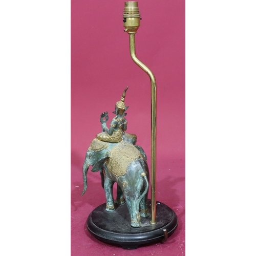 824 - An Eastern bronze and gilt metal table lamp in the form of a figure riding 3-headed elephant, mounte... 