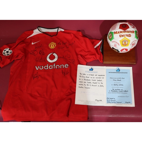 831 - A signed Manchester United signed football, donated by Bobby Charlton Teamwear 1994, with stand and ... 