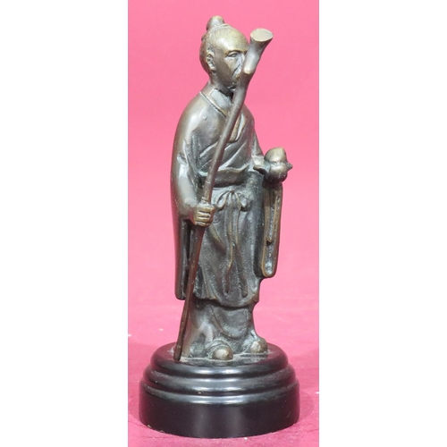 869 - A reproduction bronze figure of a standing Oriental gentleman holding a staff on black circular base... 