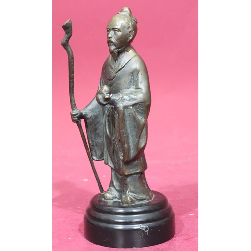 869 - A reproduction bronze figure of a standing Oriental gentleman holding a staff on black circular base... 