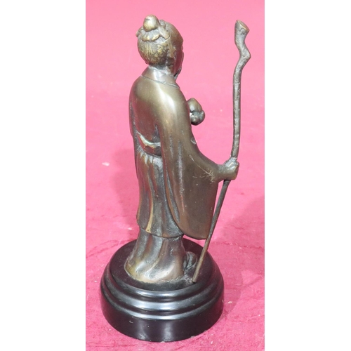 869 - A reproduction bronze figure of a standing Oriental gentleman holding a staff on black circular base... 