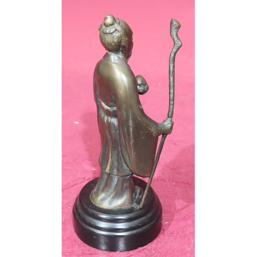 869 - A reproduction bronze figure of a standing Oriental gentleman holding a staff on black circular base... 