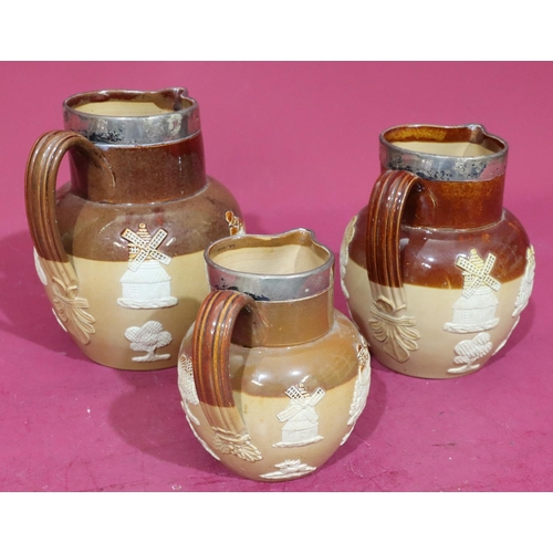 87 - A set of 3 Royal Doulton round bulbous thin neck jugs with London silver necks on brown ground with ... 