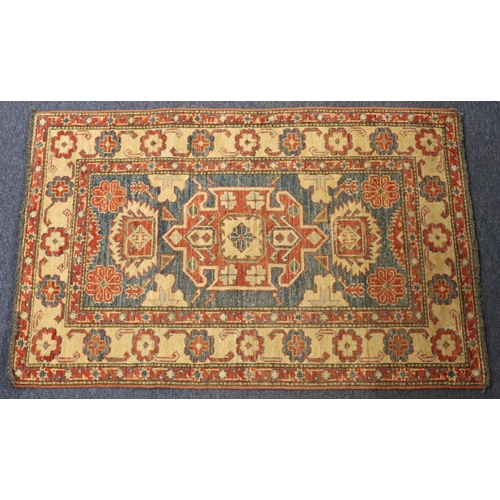 902 - A small Persian style rug on red, blue and cream ground with centre medallion surrounded by floral m... 