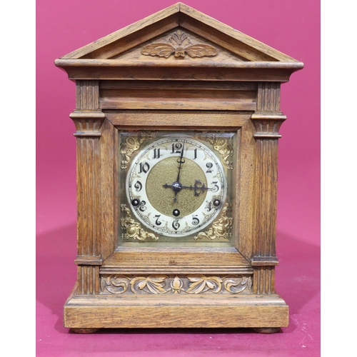 922 - An oak German 8-day striking mantel clock with carved raised floral and leaf decoration, reeded colu... 