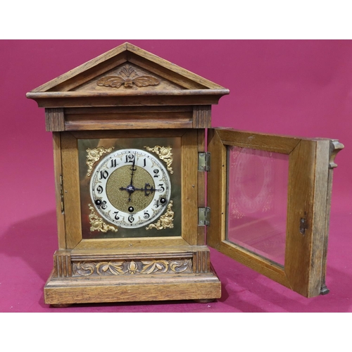 922 - An oak German 8-day striking mantel clock with carved raised floral and leaf decoration, reeded colu... 